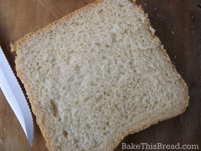 Slice of homemade yeast wheat bread using bread machine on wooden cutting board by bake this bread