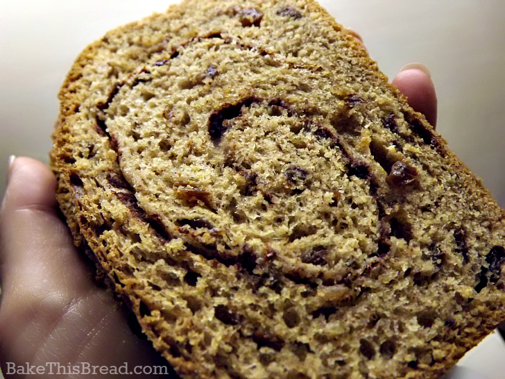 Holding a hot slice of homemade cinnamon swirl bread by bake this bread