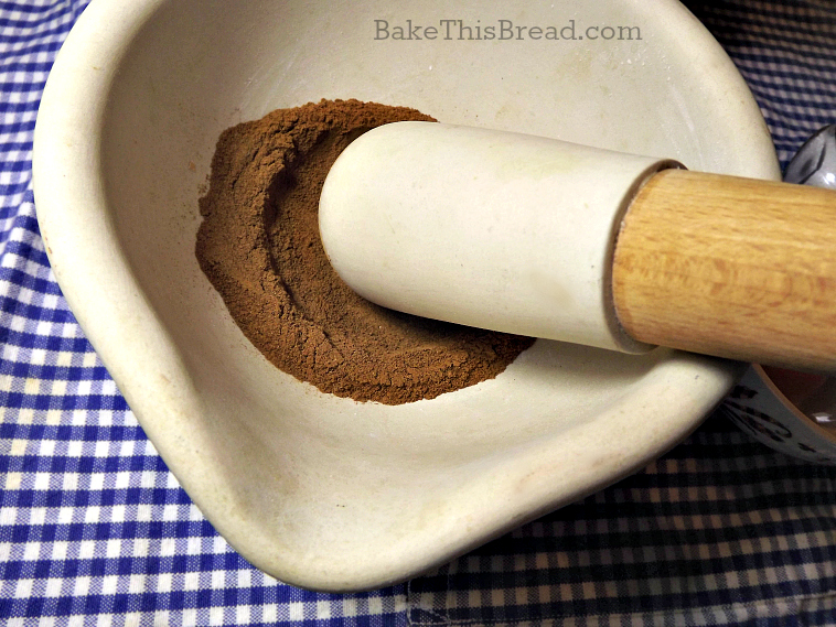 Using a mortar and pestle to grind cinnamon for homemade cinnamon bread by bake this bread